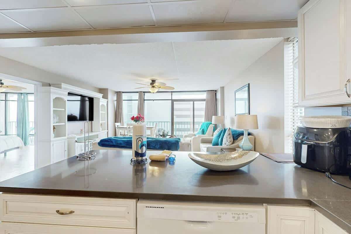 Una cocina moderna con una isla central, muebles blancos y un ventilador de techo.