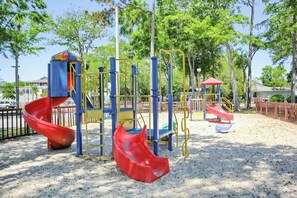 A playground with a red slide, yellow and blue play structures, and a red-roofed shelter. - Myrtle Beach Resort B-446 (Myrtle Beach)