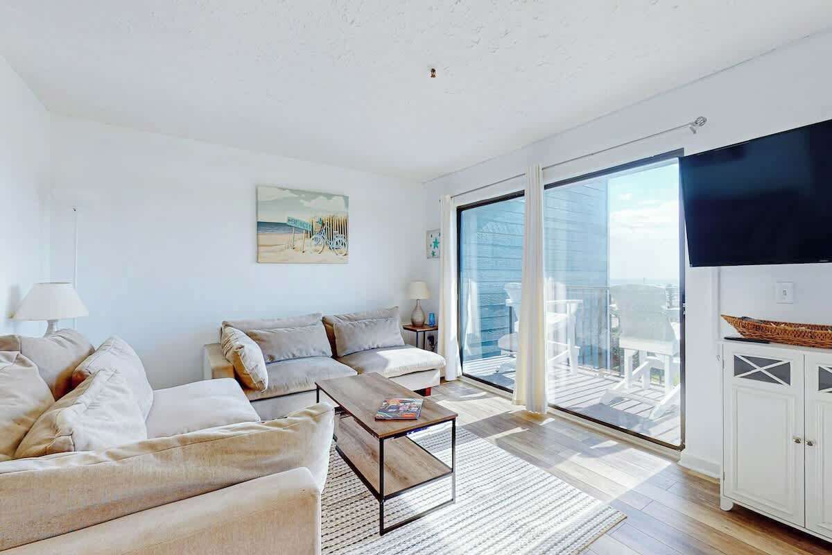 A modern living room with a sofa, a coffee table, and a view of a balcony.
