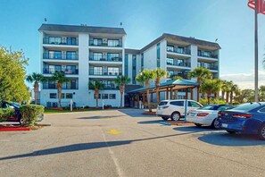 Ein mehrstöckiges Hotel mit Parkplatz und mehreren geparkten Autos davor.