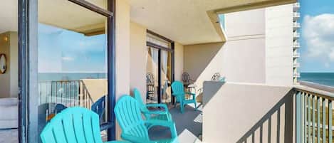 Un balcon avec des chaises turquoise et une table, donnant sur une plage.