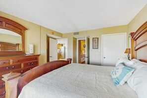 Ein Hotelzimmer mit einem großen Bett, einem hölzernen Schminktisch und einem Spiegel.