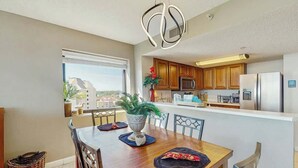Uma cozinha moderna com armários de madeira, eletrodomésticos de aço inoxidável e um espaço de jantar com mesa e cadeiras de madeira.