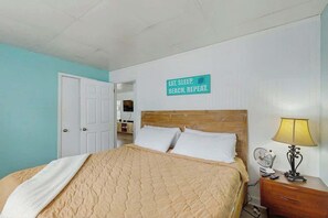 Ein Schlafzimmer mit einem Bett, einem Nachttisch, einer Lampe und einem Schild an der Wand.