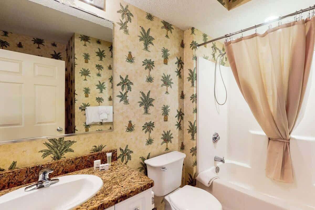 A bathroom with a sink, toilet, and shower curtain.