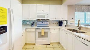 A modern kitchen with white cabinets, a built-in microwave, a stove, and a dishwasher. - North Tower Unit 301 (North Myrtle Beach)