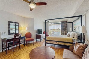 Une chambre d’hôtel avec un lit à baldaquin, un bureau avec une chaise, une table ronde et un téléviseur.