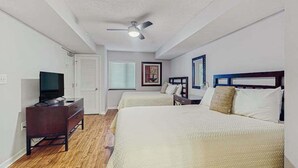 A hotel room with two beds, a dresser, a television, and a ceiling fan. - Yacht Club Villas 2-304 (North Myrtle Beach)