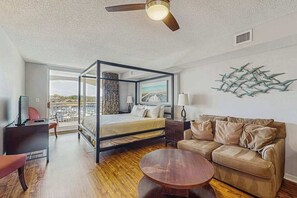 Ein modernes Schlafzimmer mit Himmelbett, einer Couch, einem Couchtisch und Blick ins Freie.