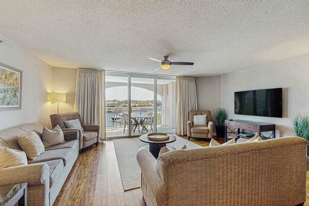 A modern living room with a sofa, armchair, and a flat-screen TV.