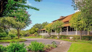 A residential property with a curved driveway, a covered porch, and a well-maintained garden. - Yacht Club Villas 2-304 (North Myrtle Beach)