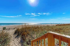 A beach with a wooden walkway leading to the water, a sandy path, and a clear blue sky. - Sand Dunes Resort 1609 (Myrtle Beach)