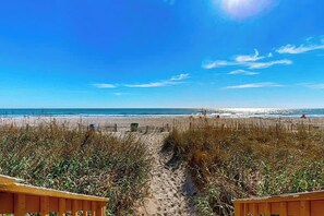 Ein Strandweg, der zum Meer führt, mit blauem Himmel.