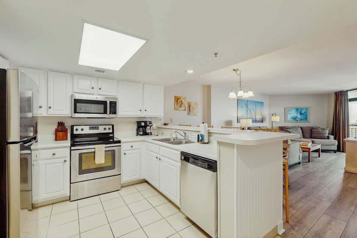 A modern kitchen with white cabinetry, a built-in oven, a microwave, and a dishwasher.