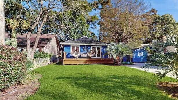 A house with a deck, surrounded by a well-maintained lawn and trees. - Lighthouse Retreat at the Beach (Myrtle Beach)