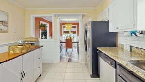A kitchen with white cabinets, a black refrigerator, and a granite countertop. - Lighthouse Retreat at the Beach (Myrtle Beach)