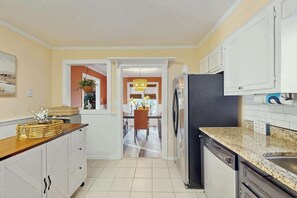 Eine Küche mit weißen Schränken, einem schwarzen Kühlschrank und einer Arbeitsplatte aus Granit.