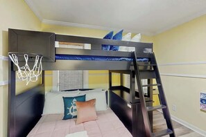 Ein Mehrbettzimmer mit Basketballkorb, einer Leiter und einem Fenster mit Jalousien.