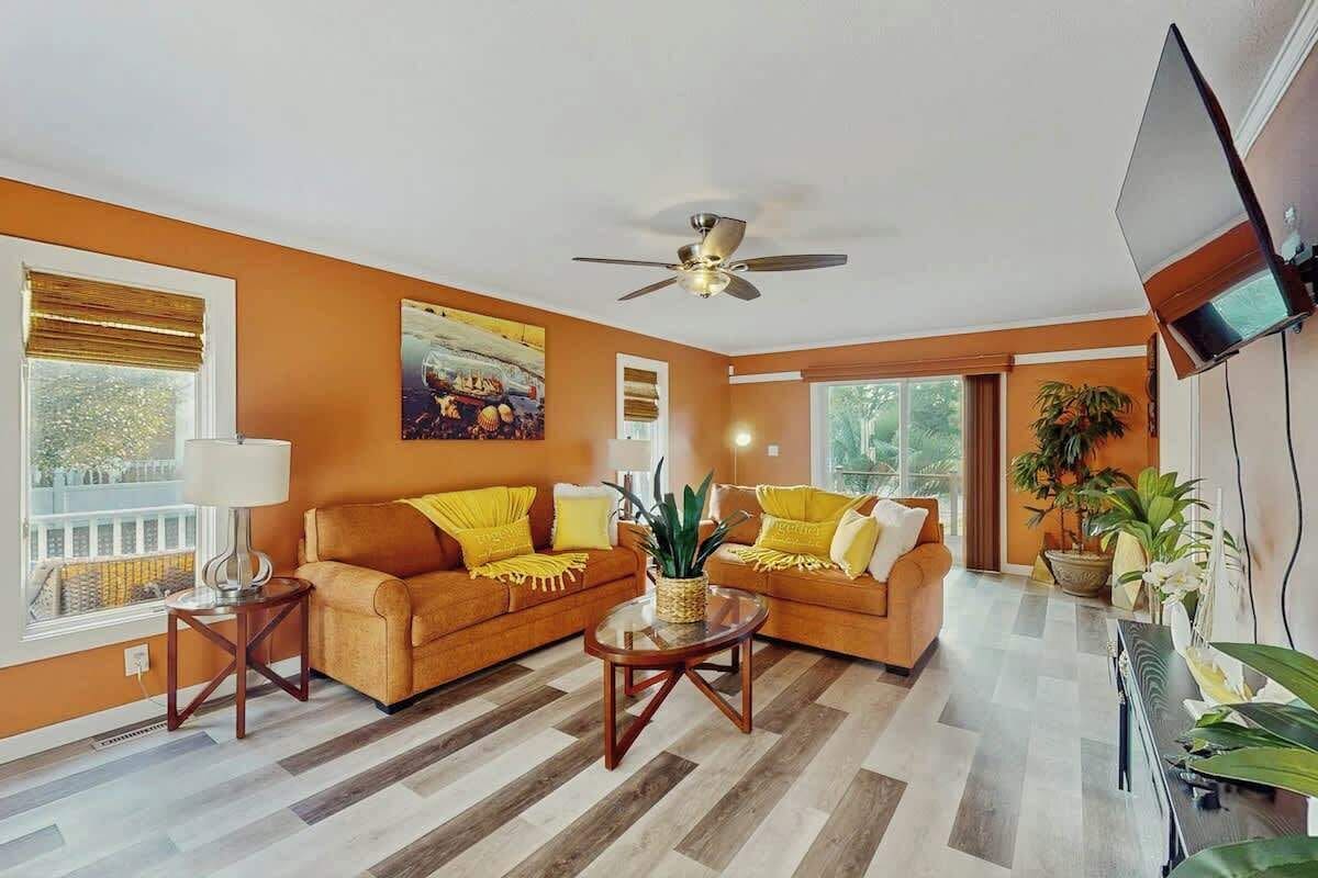 A living room with two sofas, a coffee table, a ceiling fan, and a TV mounted on the wall.