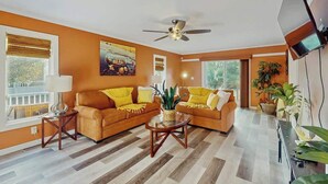 A living room with two sofas, a coffee table, a ceiling fan, and a TV mounted on the wall. - Lighthouse Retreat at the Beach (Myrtle Beach)