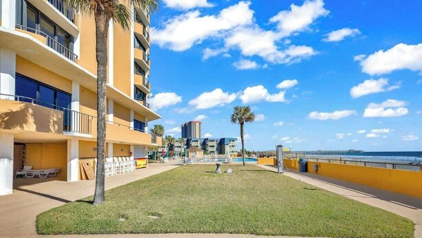 A hotel with a grassy courtyard, a palm tree, and a view of the ocean. - Maisons-sur-Mer  1507 (Myrtle Beach)