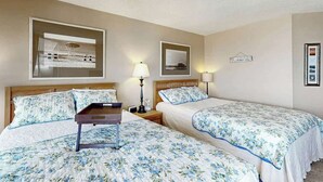 A hotel room with two beds, a nightstand, a lamp, and a framed picture on the wall. - Maisons-sur-Mer  1507 (Myrtle Beach)