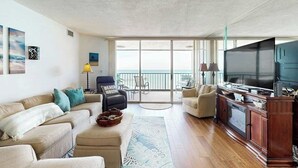 A spacious living room with a large flat-screen TV, a sofa set, a coffee table, and a view of the balcony. - Maisons-sur-Mer  1507 (Myrtle Beach)