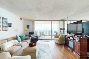 Ein geräumiges Wohnzimmer mit großem Flachbildfernseher, einer Sofagarnitur, einem Couchtisch und Blick auf den Balkon.