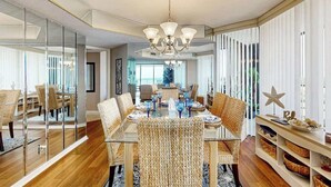 A dining area with a glass table, wicker chairs, and a chandelier. - Maisons-sur-Mer  1507 (Myrtle Beach)