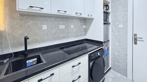 Een moderne keuken met witte kastjes, een zwart aanrecht en een ingebouwde wasmachine.