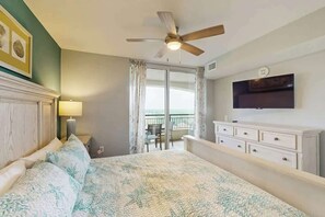 Une chambre d’hôtel avec un lit, un ventilateur de plafond, un téléviseur fixé au mur et un balcon avec vue.