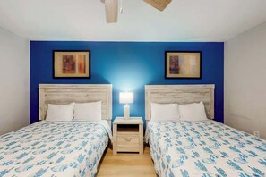 Une chambre double avec deux lits, une table de chevet entre les deux, et un ventilateur de plafond.