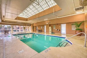 Une piscine intérieure à l’eau claire, dont la profondeur est indiquée par un repère à 90 centimètres, et qui est entourée d’une terrasse carrelée.