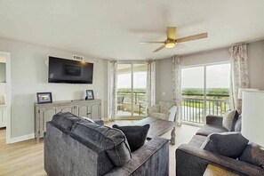 Ein Wohnzimmer mit einer Couch, einem Esstisch und einem an der Wand befestigten Fernseher.