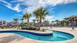 A swimming pool with a blue tiled edge, palm trees, and a clear sky. - Tilghman Beach and Golf 1519 (North Myrtle Beach)