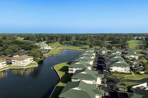 Ein Wohngebiet mit Häusern entlang eines Flusses, ein Golfplatz im Hintergrund und ein klarer Himmel.