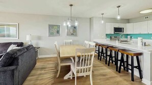 A modern kitchen with white cabinets, a central island with stools, and pendant lighting. - Tilghman Beach and Golf 1519 (North Myrtle Beach)