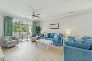 A living room with a sofa set, a coffee table, and a ceiling fan. - River Crossing at Barefoot 125 (North Myrtle Beach)