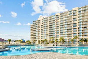 Um hotel com várias varandas, piscina e palmeiras.