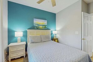 Een slaapkamer met een bed, twee nachtkastjes, een plafondventilator en een deur.