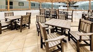 An indoor dining area with wooden tables and chairs, a tiled floor, and a high ceiling with exposed beams. - Renaissance Tower 317 (Myrtle Beach)