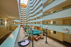 A hotel lobby with multiple floors, a central seating area with chairs and tables, and a pool. - Tilghman Beach and Golf 6003 (North Myrtle Beach)