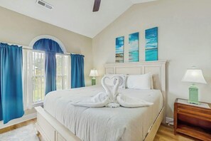 A hotel room with a large bed, a nightstand, a lamp, and a window with curtains. - Wild Iris Unit 303 Condo (Myrtle Beach)