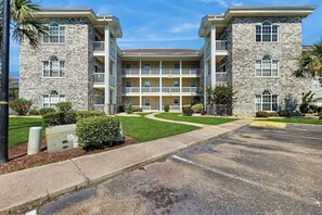 A multi-story building with a central courtyard, balconies, and a parking lot. - Wild Iris Unit 303 Condo (Myrtle Beach)