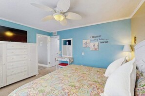 A bedroom with a bed, a dresser, a ceiling fan, a wall with a quote, and a door. - Ocean Bridge 2-C5 Sunrise Shore (Myrtle Beach)