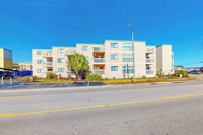 A multi-story residential building with balconies, a parking lot, and a clear sky. - Ocean Bridge 2-C5 Sunrise Shore (Myrtle Beach)