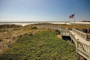 A wooden boardwalk leading to a beach with an American flag. - Ocean Creek Unit G-8 (Myrtle Beach)