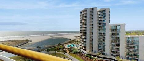 A high-rise hotel with multiple balconies overlooking a beach and ocean.