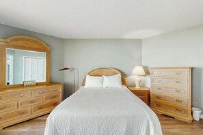 Une chambre à coucher avec un lit, une commode, une table de chevet et un miroir.