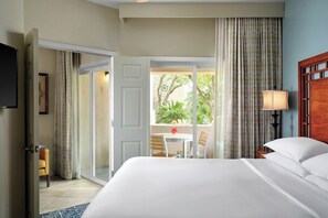 A hotel room with a bed, a table with chairs, a lamp, and a view of greenery outside. - 2 Bedroom Villa at Sheraton Desert Oasis Resort (Scottsdale)